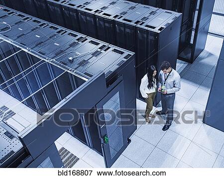 Stock Photo - High angle view of technicians talking in server room. Fotosearch