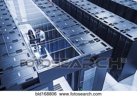 Stock Photograph - High angle view of technicians working in server room. Fotosearch