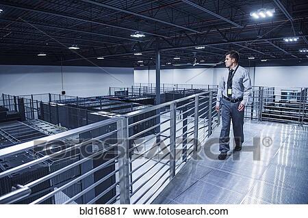 Stock Photo - Hispanic businessman examining server room from balcony. Fotosearch