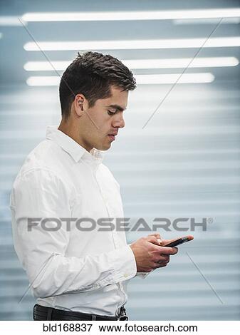 Stock Photo - Hispanic businessman using cell phone in office. Fotosearch
