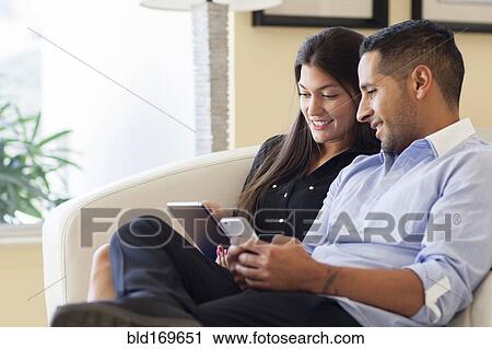 Hispanic couple using digital tablet in armchair View Large Photo Image Stock Image - Hispanic couple using digital tablet in armchair. Fotosearch