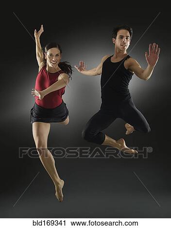 Stock Image - Hispanic dancers leaping in mid-air. Fotosearch