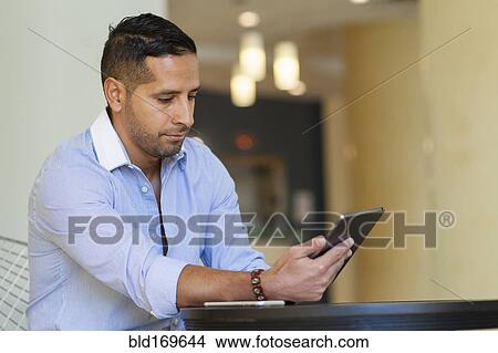 Hispanic man using digital tablet View Large Photo Image Picture - Hispanic man using digital tablet. Fotosearch