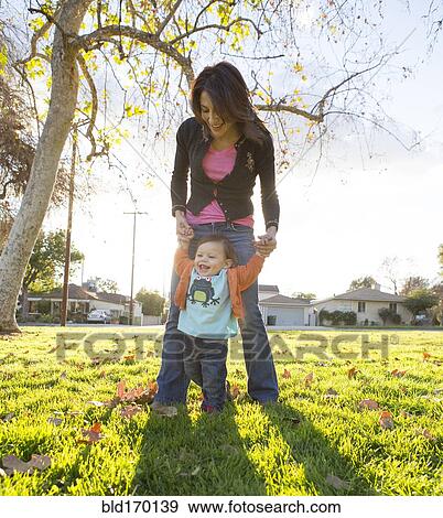 Hispanic mother playing with son in park View Large Photo Image Stock Photo - Hispanic mother playing with son in park. Fotosearch