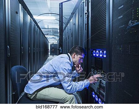 Stock Photo - Hispanic technician checking technology in server room. Fotosearch