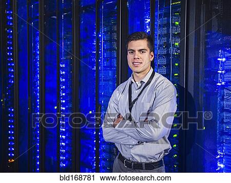 Stock Image - Hispanic technician smiling in server room. Fotosearch