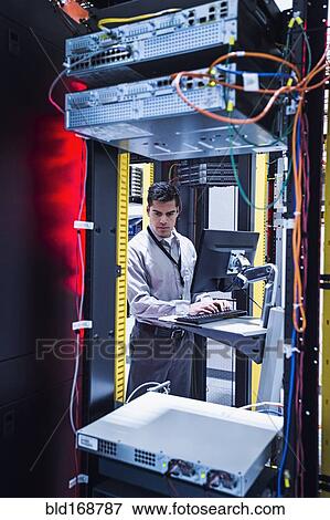 Stock Photo - Hispanic technician using computer in server room. Fotosearch