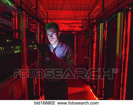 Stock Image - Hispanic technician using digital tablet in server room. Fotosearch