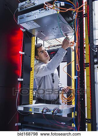 Stock Photo - Hispanic technician working in server room. Fotosearch