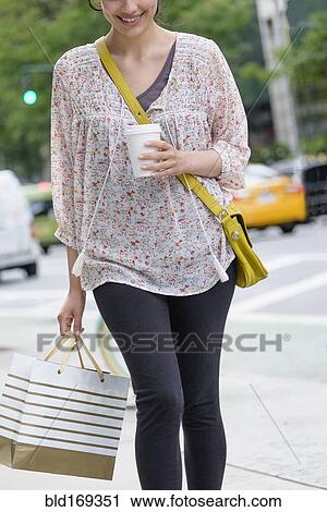 Hispanic woman carrying shopping bag on city sidewalk View Large Photo Image Stock Image - Hispanic woman carrying shopping bag on city sidewalk. Fotosearch