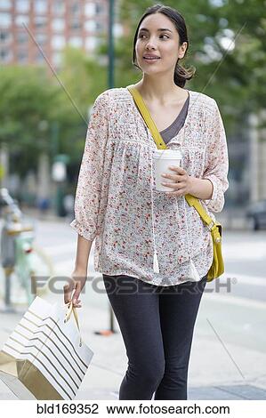 Hispanic woman carrying shopping bag on city sidewalk View Large Photo Image Stock Image - Hispanic woman carrying shopping bag on city sidewalk. Fotosearch