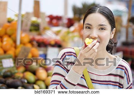 Hispanic woman eating fruit at farmers market View Large Photo Image Stock Image - Hispanic woman eating fruit at farmers market. Fotosearch