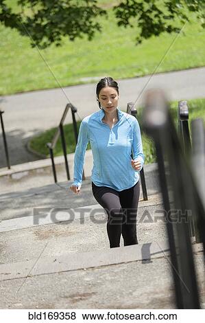 Stock Photo - Hispanic woman jogging on city steps. Fotosearch