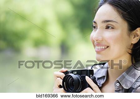 Stock Photograph - Hispanic woman photographing outdoors. Fotosearch