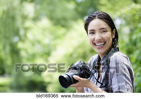 Stock Photography - Hispanic woman photographing outdoors. Fotosearch