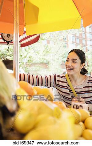 Stock Photo - Hispanic woman shopping at farmers market. Fotosearch
