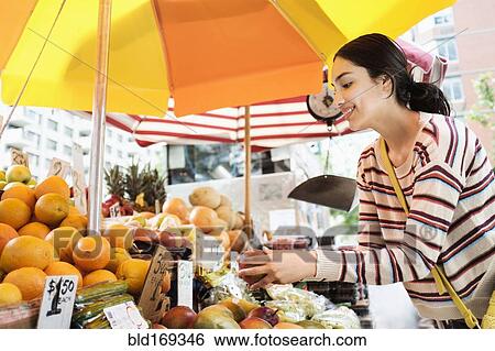 Stock Photograph - Hispanic woman shopping at farmers market. Fotosearch