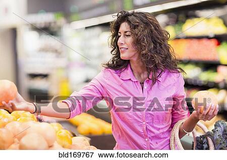 Stock Photo - Hispanic woman shopping at grocery store. Fotosearch