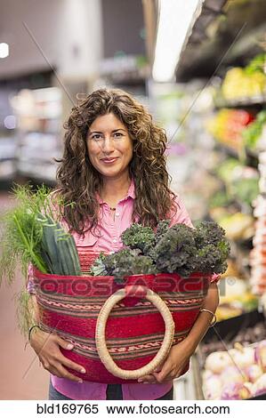 Stock Photography - Hispanic woman shopping at grocery store. Fotosearch