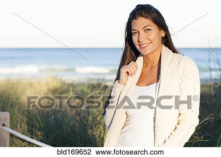 Stock Image - Hispanic woman smiling on beach. Fotosearch