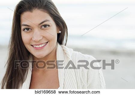 Stock Photo - Hispanic woman smiling on beach. Fotosearch