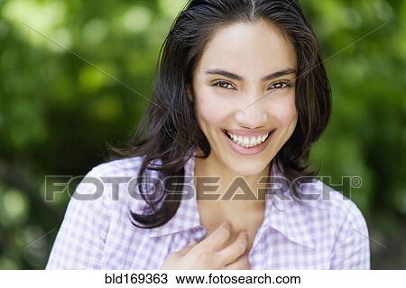 Stock Image - Hispanic woman smiling outdoors. Fotosearch