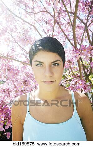 Stock Photography - Hispanic woman standing under flowering tree. Fotosearch