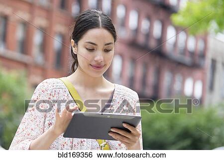 Hispanic woman using digital tablet in city View Large Photo Image Stock Photograph - Hispanic woman using digital tablet in city. Fotosearch