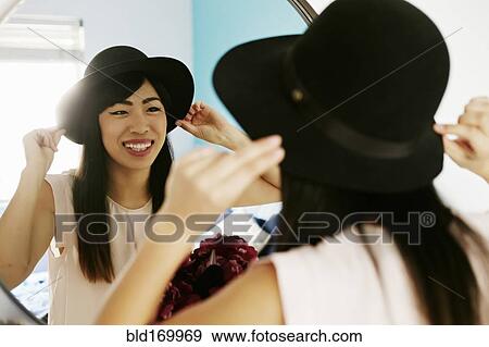 Japanese woman adjusting hat in mirror View Large Photo Image Stock Photo - Japanese woman adjusting hat in mirror. Fotosearch