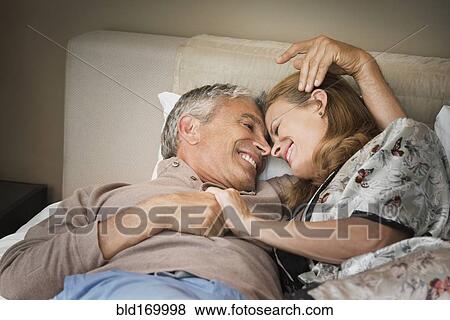 Laughing couple relaxing on bed View Large Photo Image Stock Photo - Laughing couple relaxing on bed. Fotosearch