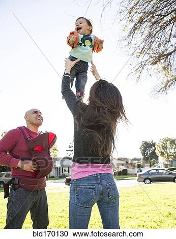 Stock Image - Low angle view of Hispanic family playing in park. Fotosearch