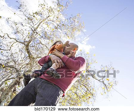 Stock Photo - Low angle view of Hispanic father kissing son outdoors. Fotosearch