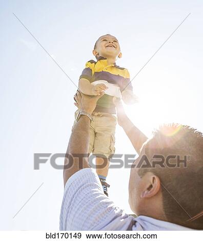Low angle view of Hispanic father lifting son in air View Large Photo Image Stock Photo - Low angle view of Hispanic father lifting son in air. Fotosearch