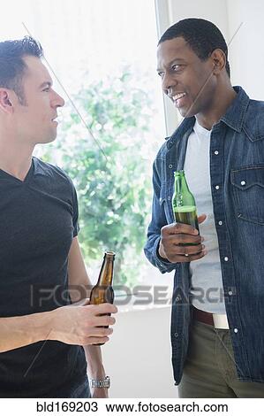 Stock Image - Men drinking beer near window. Fotosearch