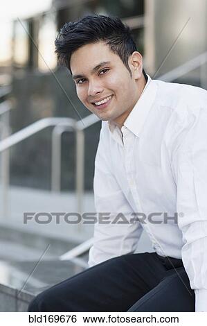 Stock Photograph - Mixed race businessman smiling near staircase. Fotosearch