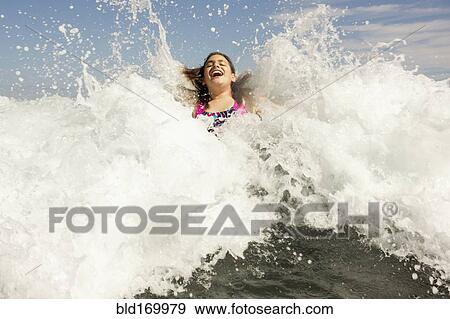 Stock Photo - Mixed race girl playing in ocean waves. Fotosearch
