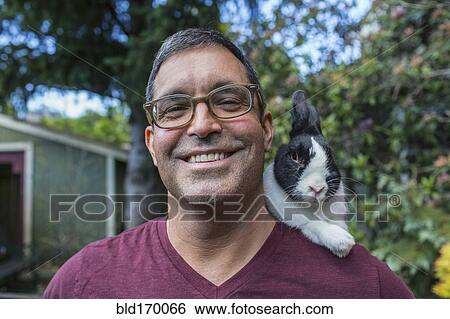 Stock Photograph - Mixed race man carrying rabbit on shoulder. Fotosearch