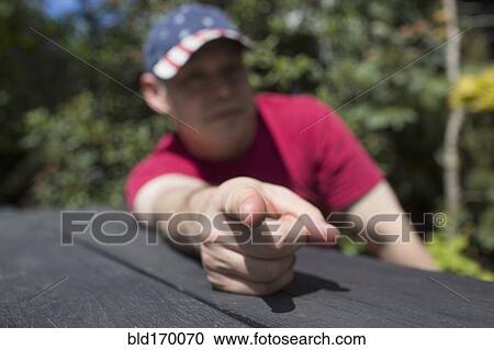Stock Image - Mixed race man pointing finger on picnic table. Fotosearch