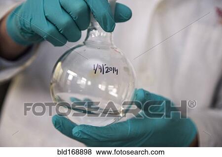 Stock Photo - Mixed race scientist mixing solution in lab. Fotosearch