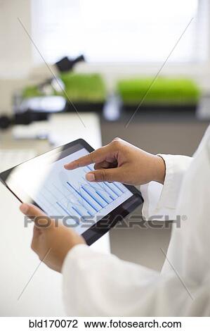 Stock Image - Mixed race scientist using digital tablet in laboratory. Fotosearch