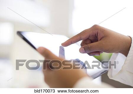 Stock Image - Mixed race scientist using digital tablet in laboratory. Fotosearch