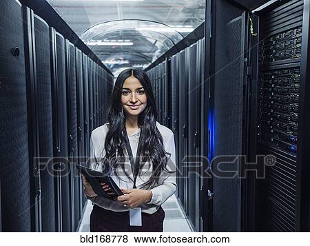 Stock Photo - Mixed race technician holding digital tablet in server room. Fotosearch