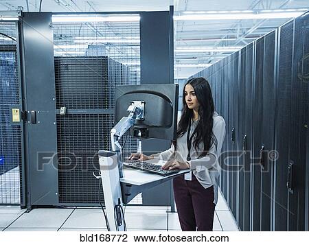 Mixed race technician using computer in server room View Large Photo Image Stock Image - Mixed race technician using computer in server room. Fotosearch