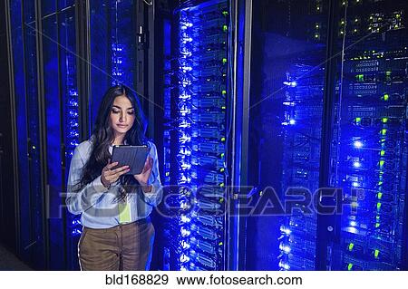 Stock Photo - Mixed race technician using digital tablet in server room. Fotosearch
