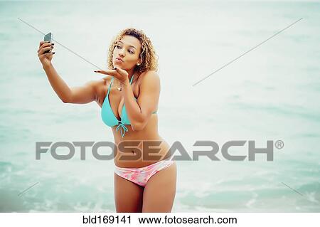 Mixed race teenager taking selfie in bikini on beach View Large Photo Image Stock Image - Mixed race teenager taking selfie in bikini on beach. Fotosearch