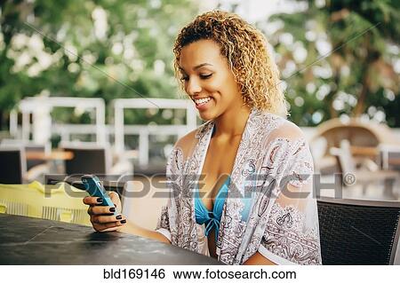 Mixed race teenager using cell phone at table View Large Photo Image Stock Photograph - Mixed race teenager using cell phone at table. Fotosearch