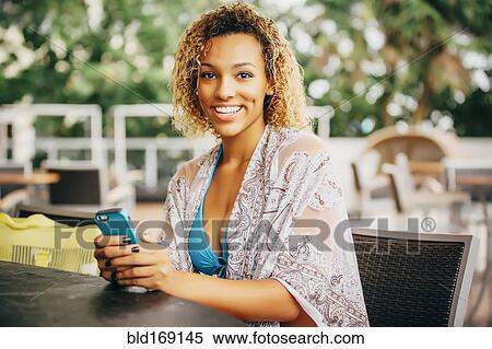 Mixed race teenager using cell phone at table View Large Photo Image Stock Photography - Mixed race teenager using cell phone at table. Fotosearch