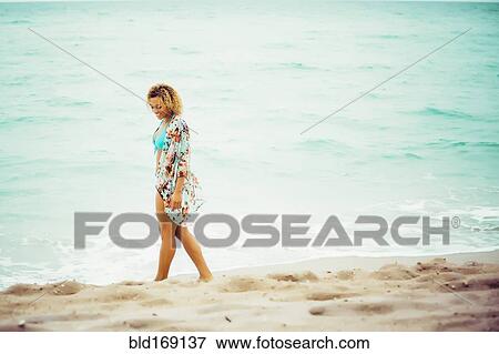 Stock Photo - Mixed race teenager wearing cover-up on beach. Fotosearch