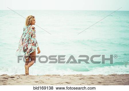 Stock Photo - Mixed race teenager wearing cover-up on beach. Fotosearch