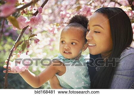 Stock Image - Mother and daughter admiring flowering tree in park. Fotosearch